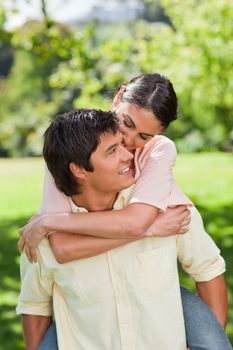 Man smiling and looking at his friend while he is holding her on his back