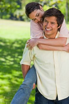 Woman smiling as she watches her friend while he carries her around on his back