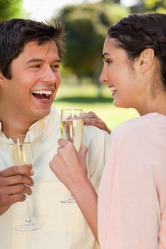 Man and a woman looking at each other and laughing while holding glasses of champagne