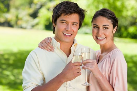 Man and a woman smiling while they touch glasses of champagne in celebration