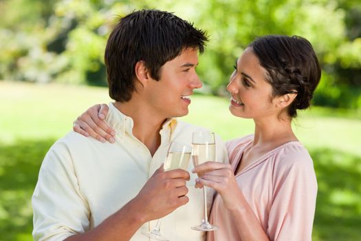 Man and a woman smiling happily as they look at each other while touching glasses of champagne in celebration