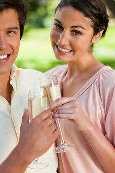 Woman smiling joyfully while touching glasses of champagne with her friend in celebration