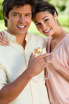 Woman smiling and leaning against her smiling friend while touching glasses of champagne in celebration