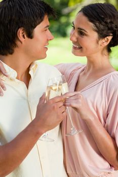 Man and a woman smiling and holding each other while touching glasses of champagne in celebration