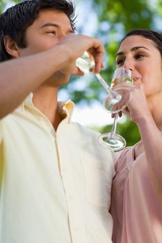 Woman and a man looking at each other while drinking a glass of champagne each