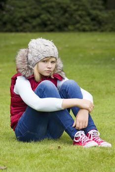 young girl sitting on the grass in the park