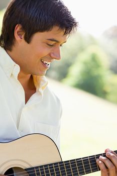 Man looking downwards and smiling while playing a guitar