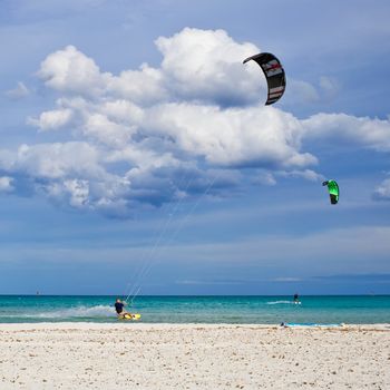 Kitesurfers gliding at high speed around the beach Cinta, Sardinia