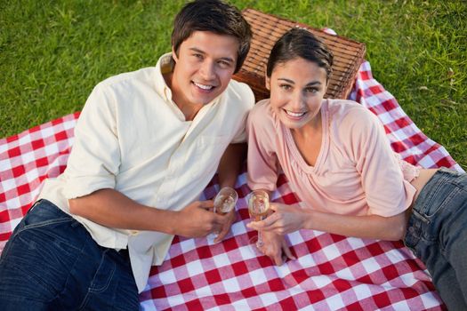 Man and a woman looking towards the sky while lying on a red and white picnic blanket