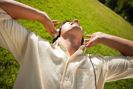 Man singing while using headphones to listen to music as he lies in grass