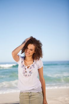 Young woman standing upright with her hand on her head in front of the sea