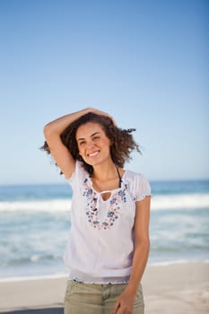 Young smiling woman holding her hair in front of the sea