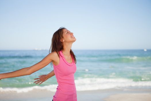 Young woman standing with arms back while sunbathing on the beach