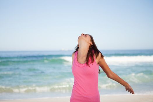 Young relaxed woman standing in front of the sea while sunbathing