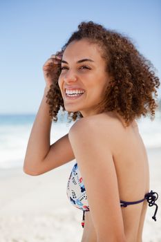 Smiling woman looking towards the side while raising her hand next to her ear