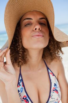 Young attractive woman standing upright on the beach with puckered lips