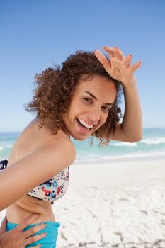 Young woman putting her hand on her forehead to look at the camera while smiling