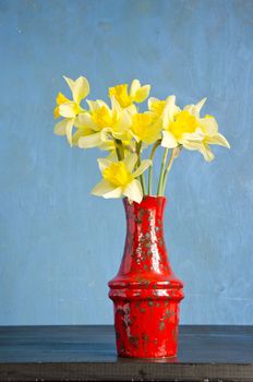 red vase on black table with spring narcissus