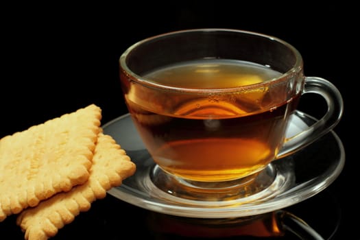 Cup of tea with biscuits on black background