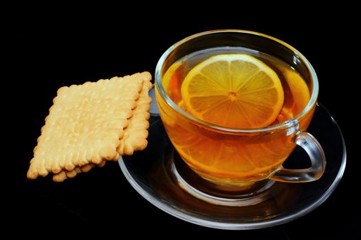 Cup of tea with biscuits and limon on black background