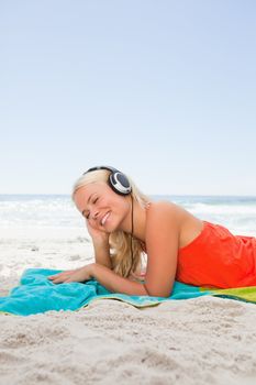 Young blonde woman lying down while listening to music with her headset