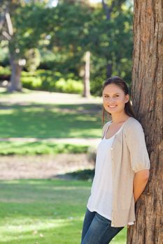 Smiling young woman leaning against a tree