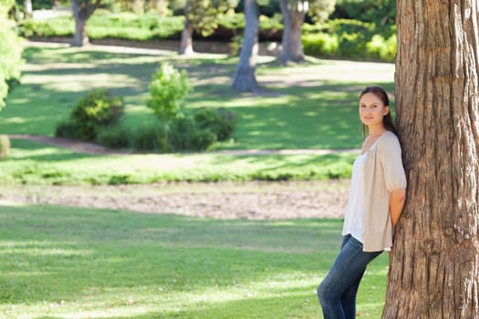 Young woman leaning against a tree in the park