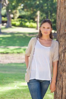 Young woman resting against a tree