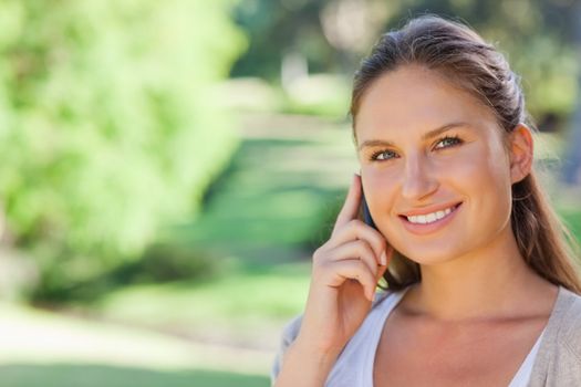 Smiling young woman on her phone in the park