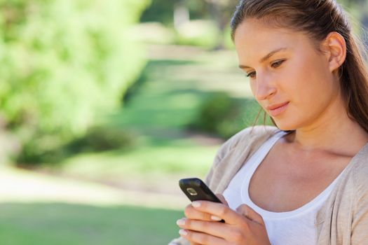 Close up of young woman reading a text message in the park