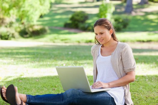 Young woman sitting on the lawn with her laptop