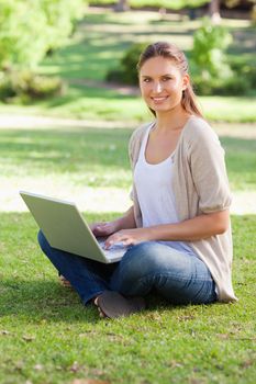 Smiling young woman working on her notebook in the park