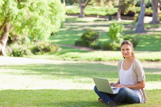 Young woman with her laptop sitting in the park