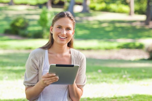Smiling young woman in the park with her tablet computer