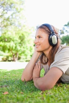 Side view of a young woman listening to music on the lawn