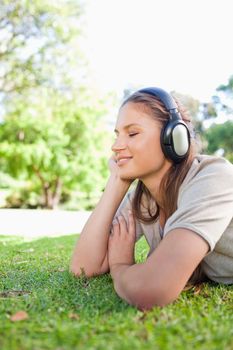 Side view of a young woman enjoying music on the lawn