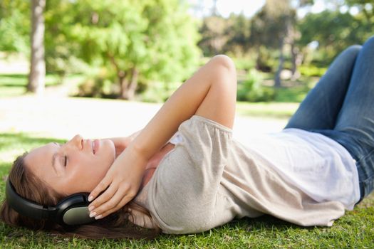Young woman lying on the lawn while enjoying music