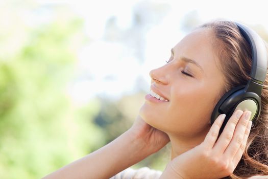 Side view of a young woman enjoying music in the park