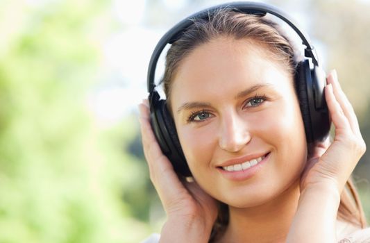 Close up of a young woman listening to music in the park