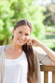 Smiling young woman sitting on a bench in the park