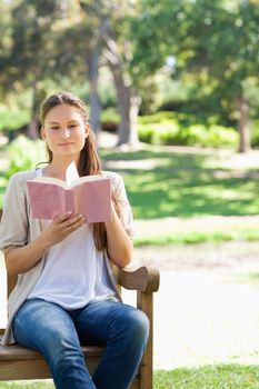 Young woman reading a book on a park bench