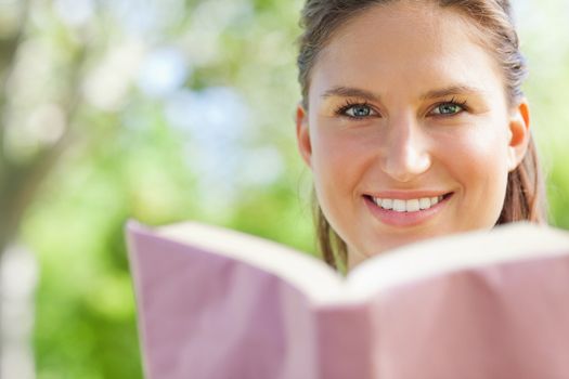 Smiling young woman reading a book in the park