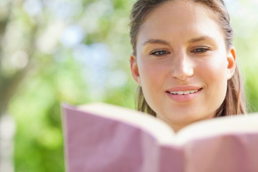 Young woman reading her book in the park