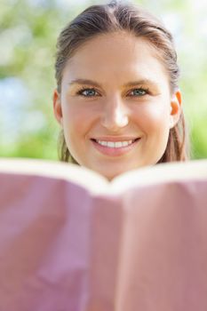 Smiling young woman with her book in the park