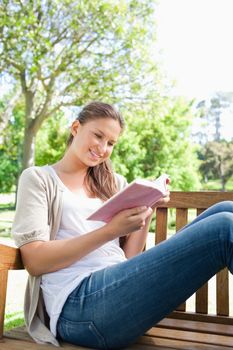 Young woman reading a book while sitting on a bench