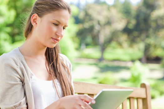 Young woman with her tablet computer sitting on a park bench