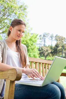 Young woman on a park bench with her laptop