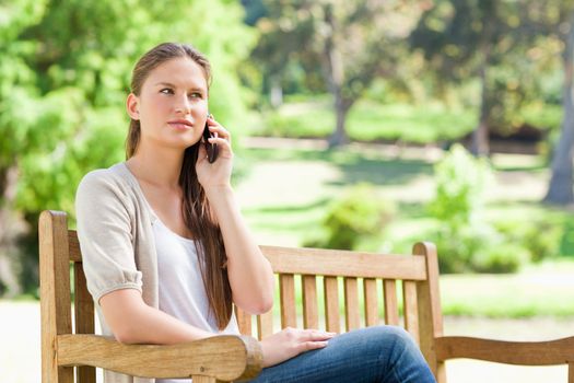 Young woman on her mobile phone on a park bench