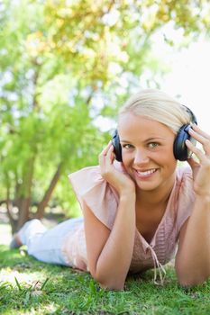 Smiling young woman enjoying music on the lawn