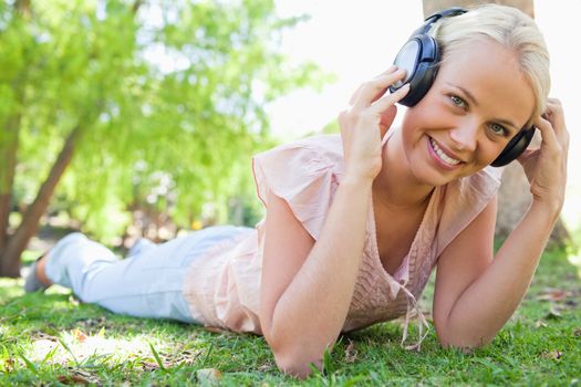 Smiling young woman enjoying music on the grass